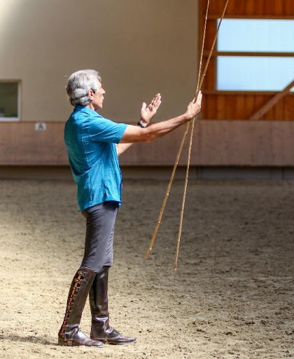 Manolo Mendez holding bamboo sticks to aid in horse training